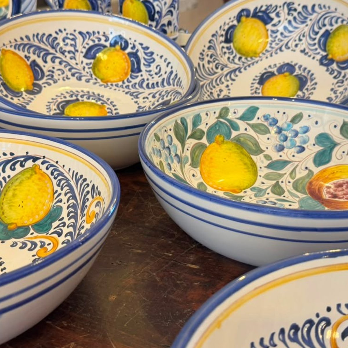 Ciotola in ceramica con limoni gialli e foglie su fondo bianco, bordo blu