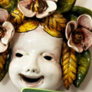 Maschera da parete in ceramica: volto con fiori e foglie applicati