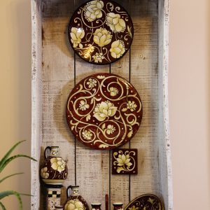 Composizione a parete con piatti color bruno e fiori crema
