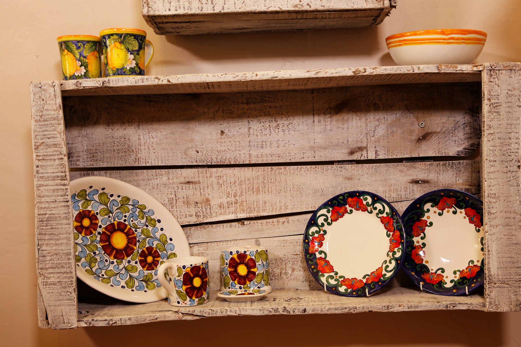 Red and black hand-painted plates in a wooden crate