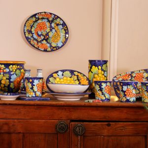 Servizio con decoro a grappoli su fondo blu su credenza in noce