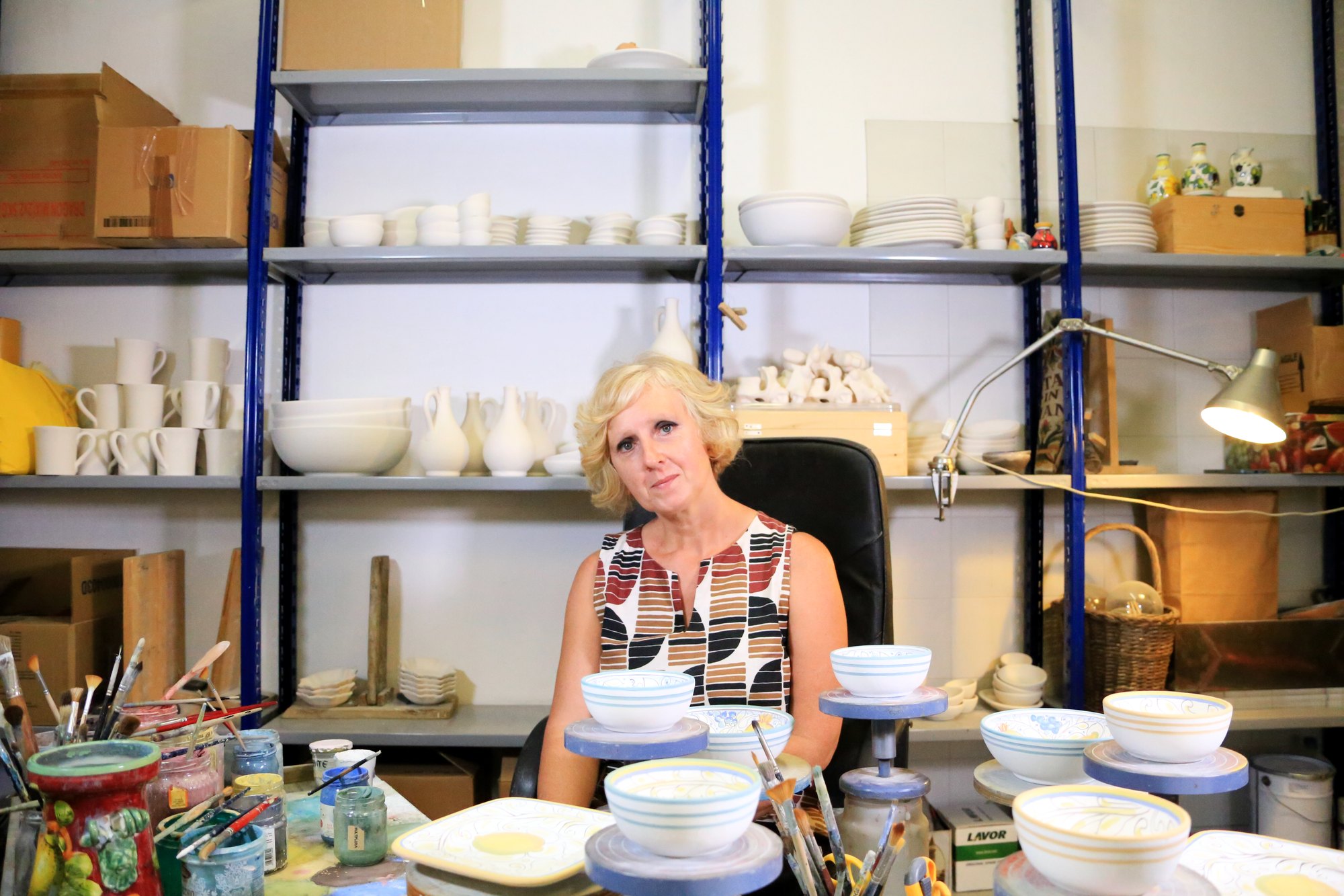 Gabriella Carbini in her workshop, with shelves of biscuit-fired pieces