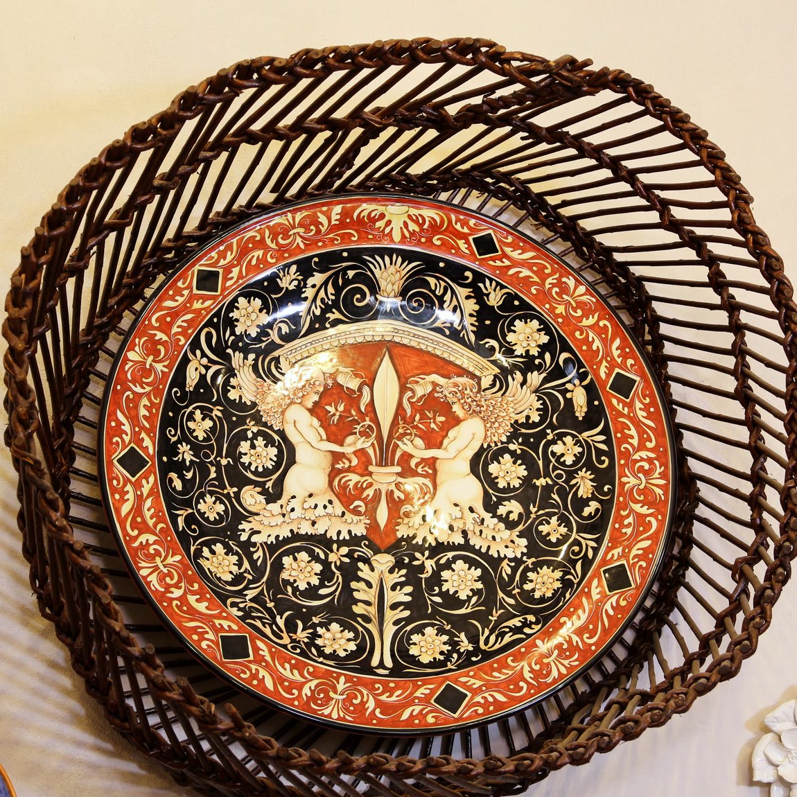 Piatto da parete raffaellesco con putti alati e giglio su fondo nero e bordo rosso (2)