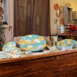 Tavola allestita con il servizio turchese e oro sulla cassapanca